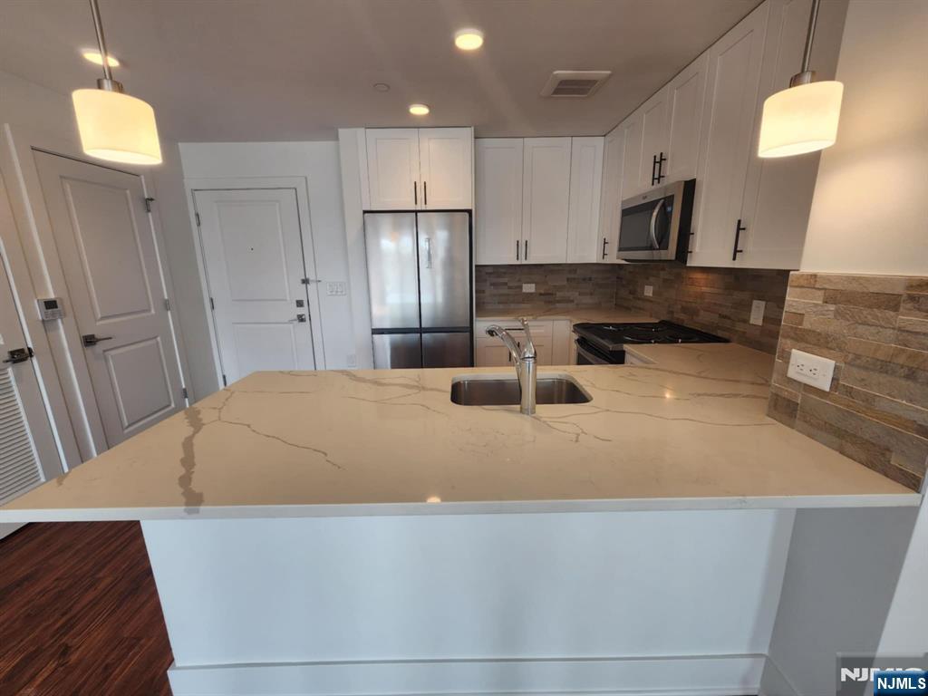 77 Ridge, Unit 108 North Arlington, NJ 07032 - Photo 6 of 24 a large white kitchen with wooden floors