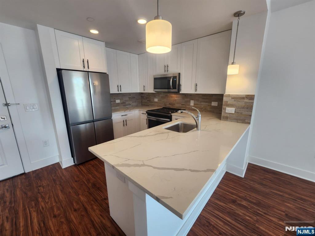 77 Ridge, Unit 108 North Arlington, NJ 07032 - Photo 7 of 24 a kitchen with stainless steel appliances granite countertop a refrigerator a stove a sink dishwasher and a microwave with wooden floor