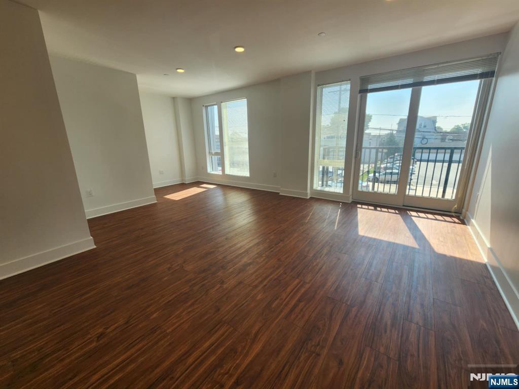 77 Ridge, Unit 108 North Arlington, NJ 07032 - Photo 8 of 24 a view of an empty room with wooden floor and a window