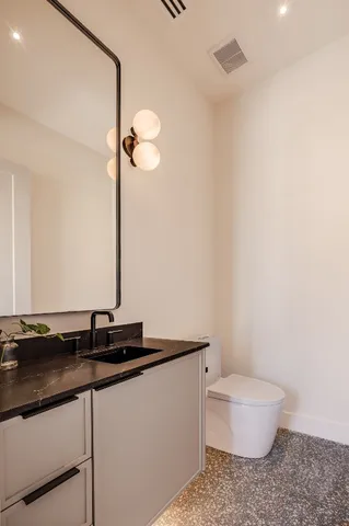 a bathroom with a granite countertop sink a toilet and a mirror