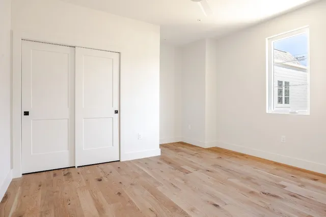 a view of an empty room with wooden floor and a window