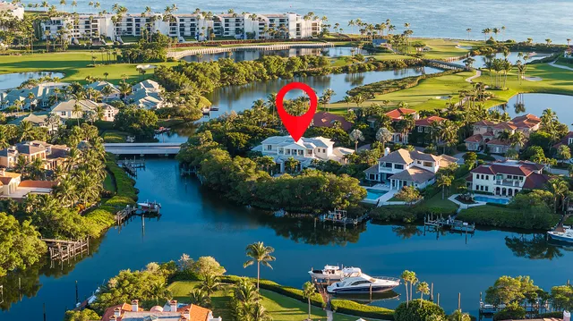 an aerial view of a house with a lake boats and trees all around