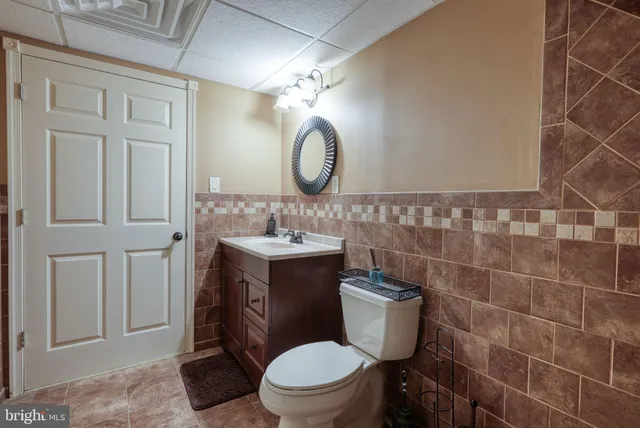 a bathroom with a toilet sink vanity and mirror