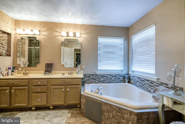 a spacious bathroom with a tub sink and mirror