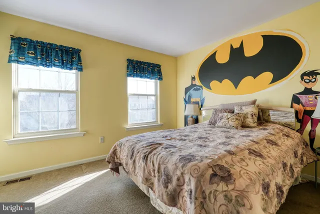 a bedroom with a bed and dresser with wooden floor