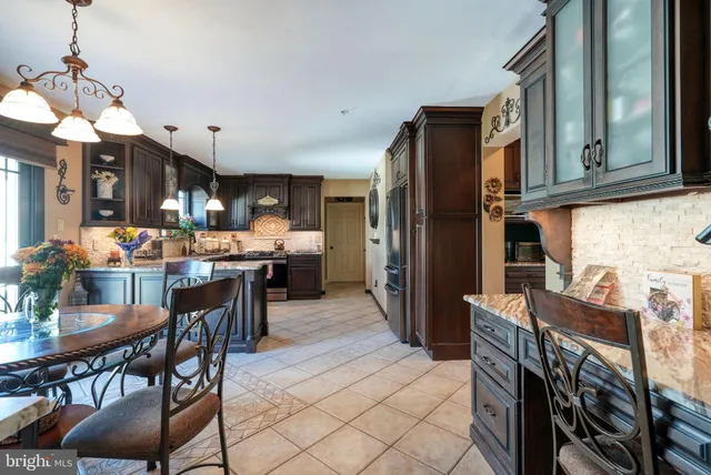 a kitchen with stainless steel appliances kitchen island granite countertop a refrigerator a stove a sink a dining table and chairs with wooden floor