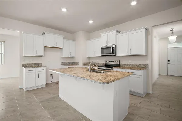 a kitchen with granite countertop white cabinets and stainless steel appliances
