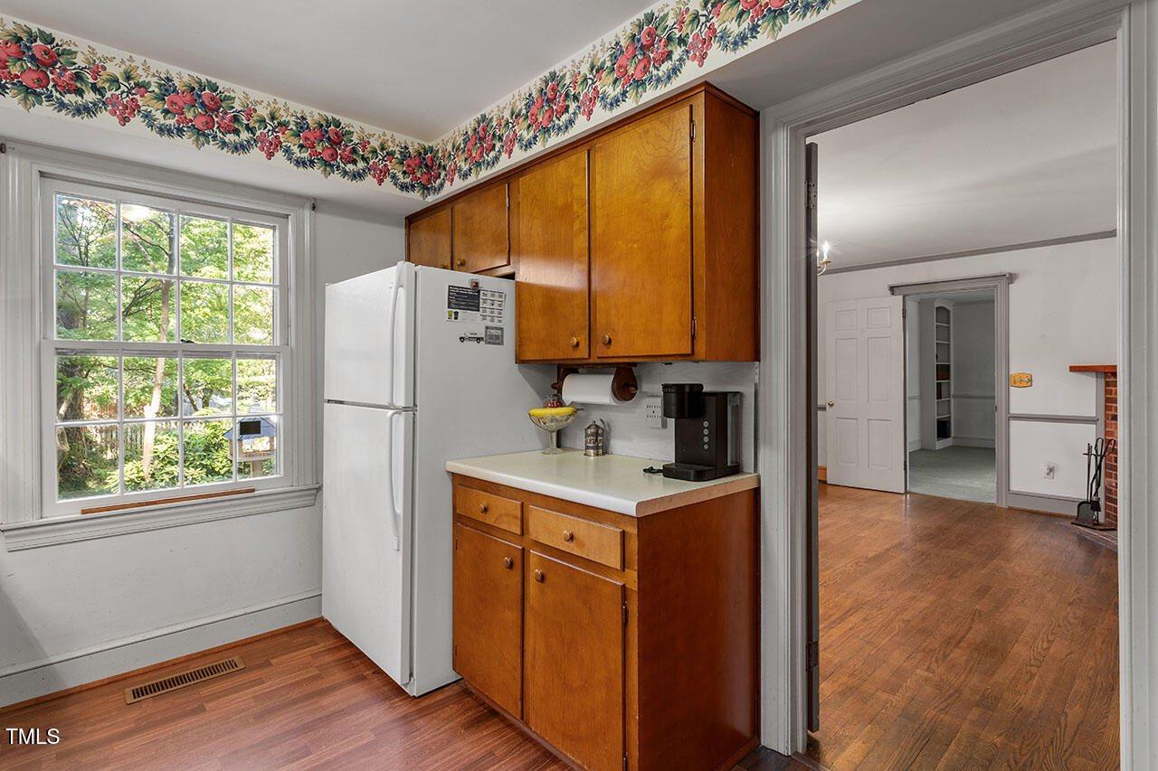 3408 Caldwell Drive Raleigh, NC 27607 - Photo 28 of 46 a kitchen with granite countertop a refrigerator a sink dishwasher and wooden cabinets with wooden floor