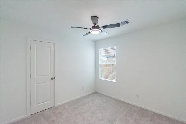 an empty room with windows and fan