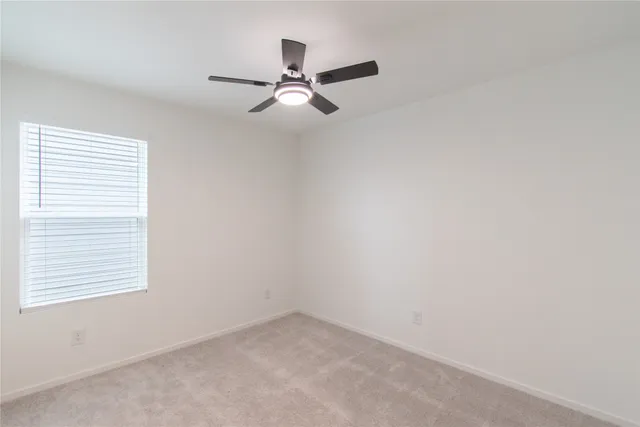 an empty room with a window and a fan