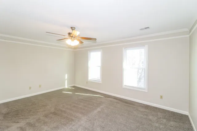 an empty room with windows and chandelier fan