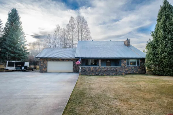 a front view of a house with yard and trees