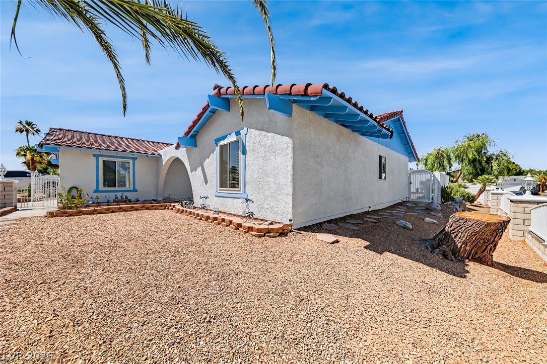 3107 Trueno Road Henderson, NV 89014 - Photo 7 of 37 A charming stucco home with a terracotta tile roof and vibrant blue accents offers desert-friendly gravel landscaping.
