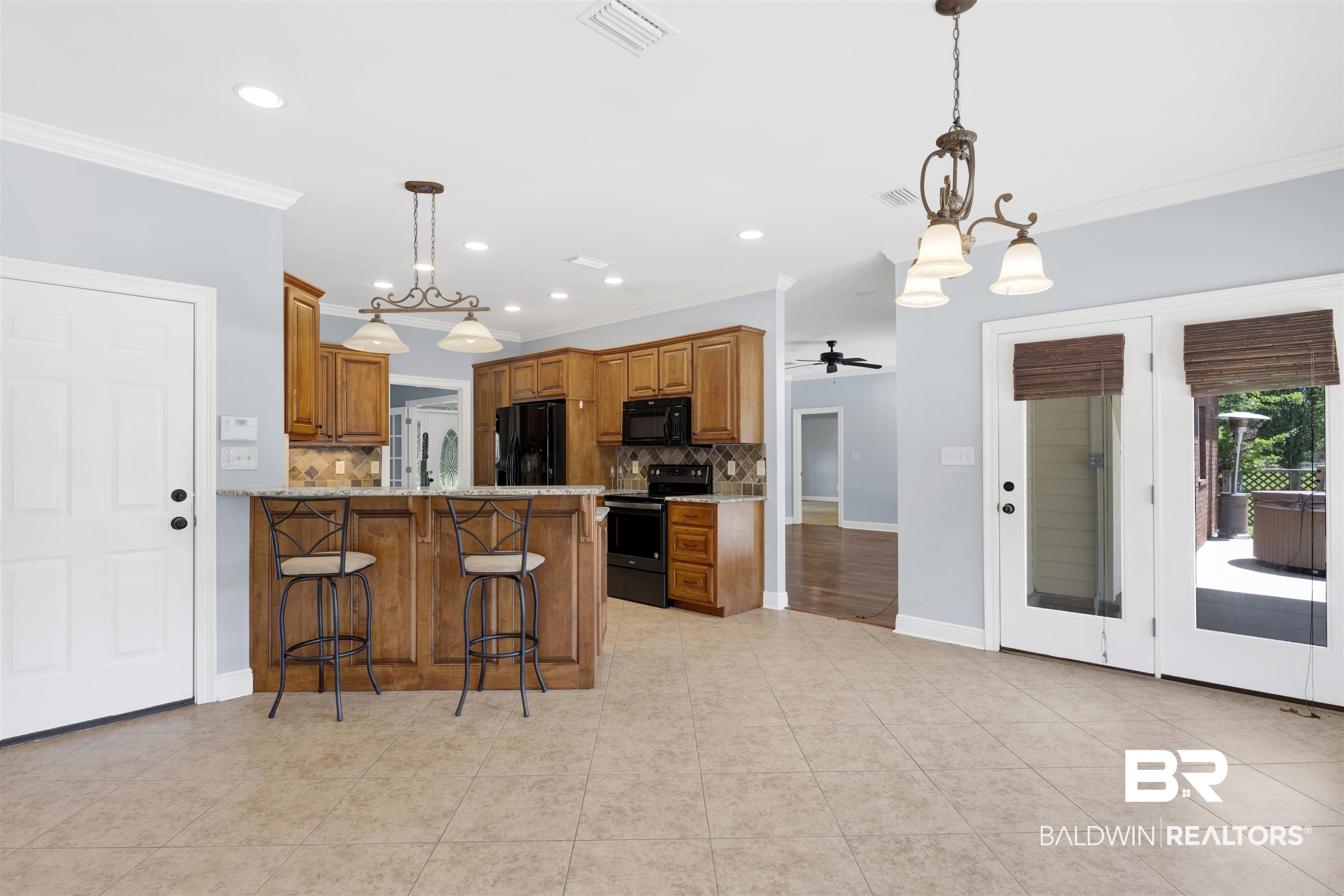 12944 Anna's Way Stapleton, AL 36578 - Photo 40 of 64 Spacious kitchen featuring warm wood cabinetry, black appliances, a tile backsplash, and a breakfast bar with pendant lighting
