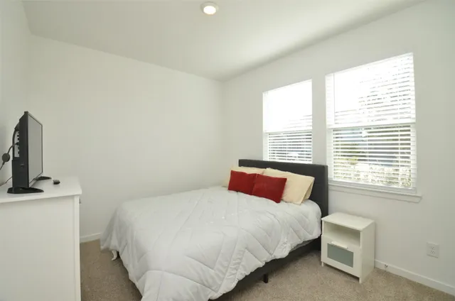 a bedroom with a bed a window and a flat screen tv
