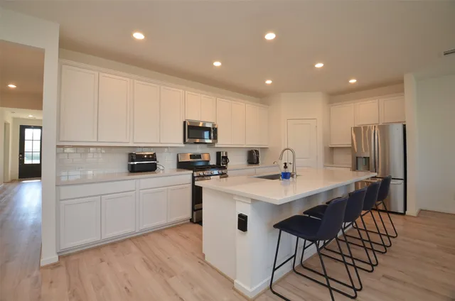 a kitchen with white cabinets stove and refrigerator
