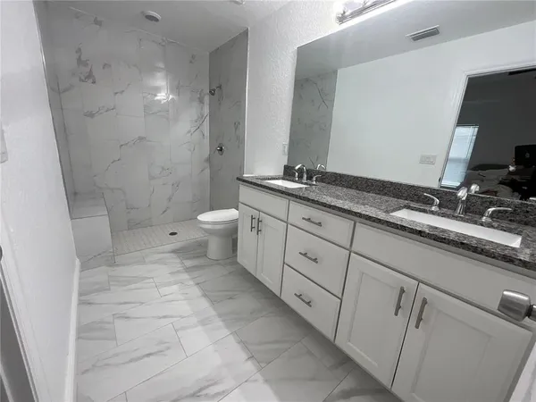 a spacious bathroom with a granite countertop sink toilet and shower