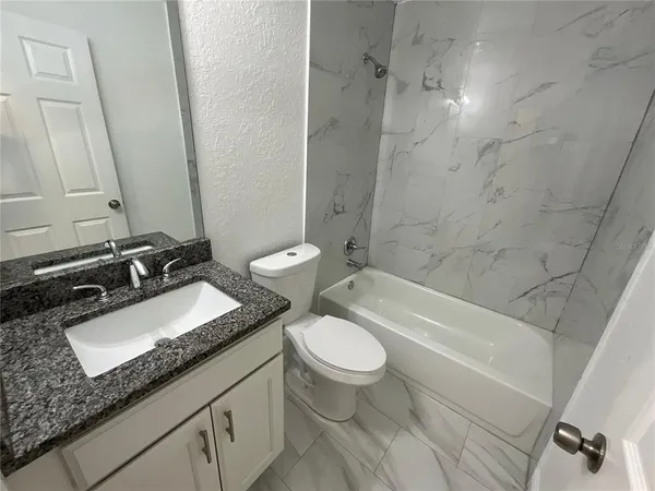 a bathroom with a granite countertop toilet a sink and a bathtub