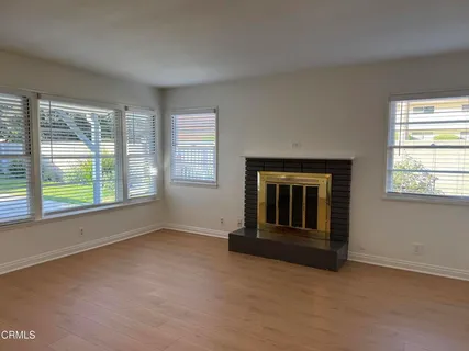 an empty room with windows and fireplace