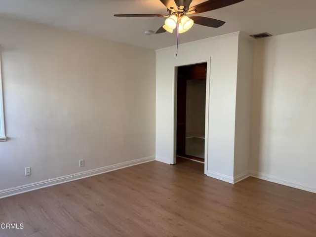 a view of an empty room with a window and wooden floor