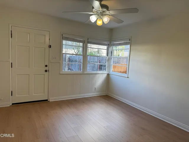 an empty room with wooden floor chandelier fan and windows