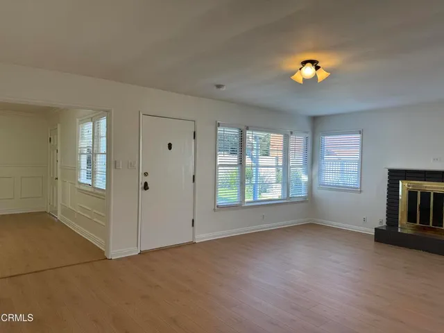 an empty room with windows and chandelier fan