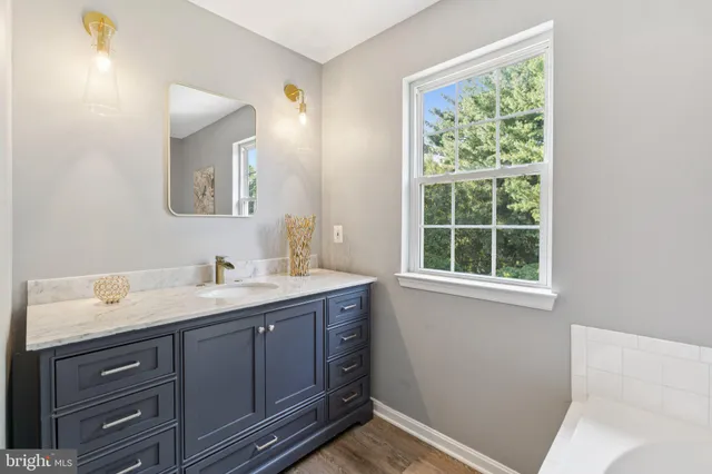 a bathroom with a granite countertop sink mirror and a window