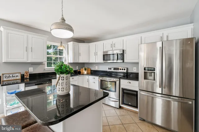 a kitchen with stainless steel appliances granite countertop a refrigerator a stove a sink a dining table and chairs