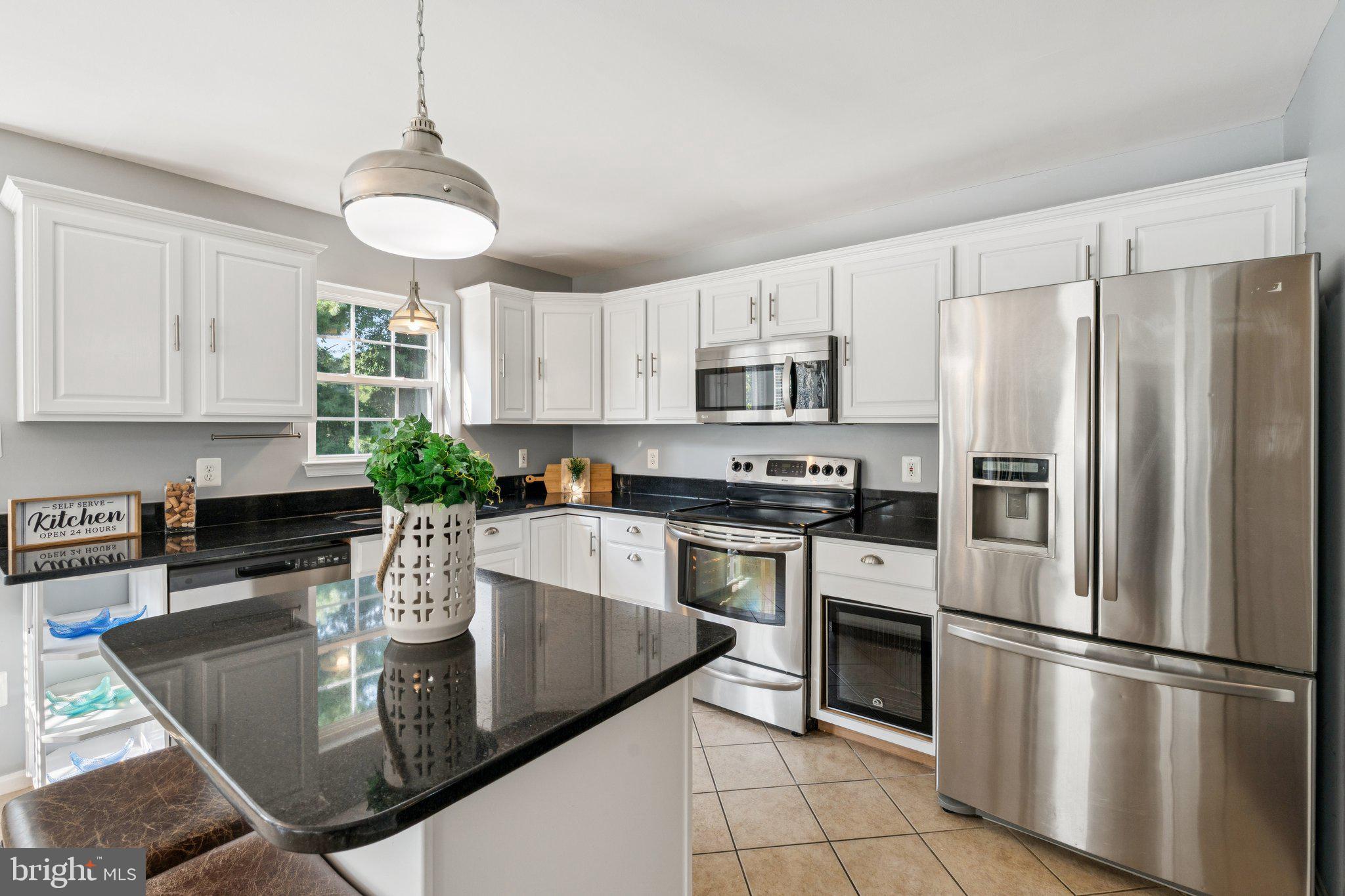 2050 Horace Ward Road Owings, MD 20736 - Photo 7 of 39 a kitchen with stainless steel appliances granite countertop a refrigerator a stove a sink a dining table and chairs