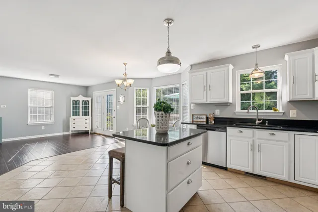 a kitchen with granite countertop white cabinets white appliances a sink and a window