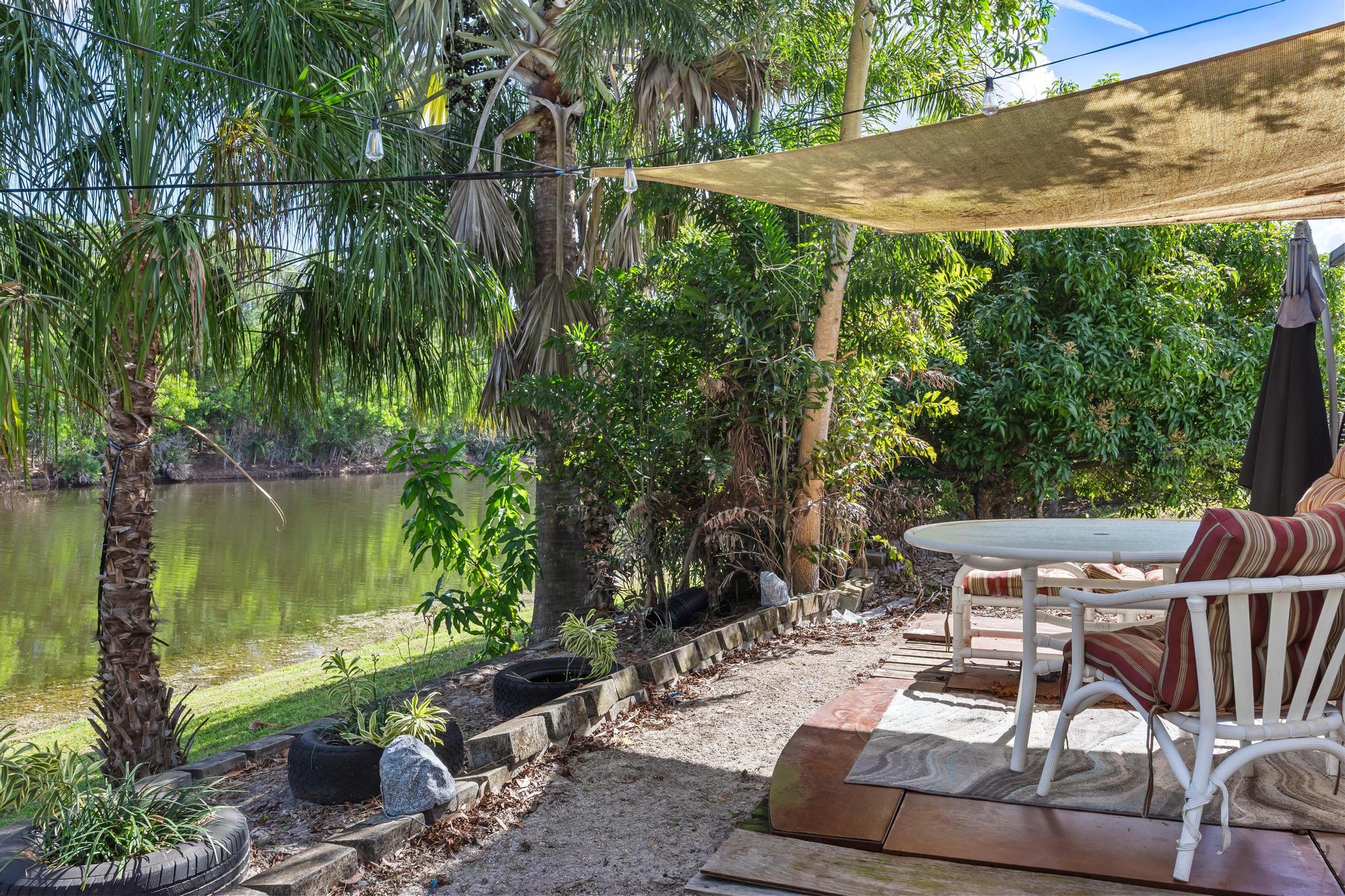 3337 Southwest Crestview Road Port St. Lucie, FL 34953 - Photo 63 of 86 a view of a patio with table and chairs potted plants with lake view