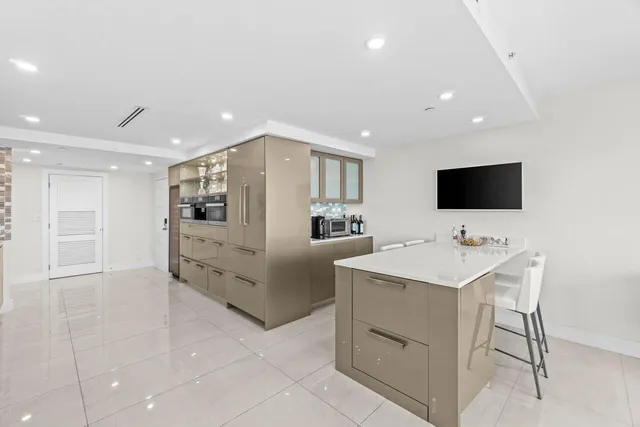 a view of a kitchen with kitchen island a sink stainless steel appliances and white cabinets