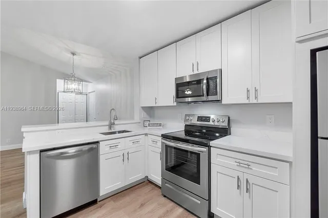 a kitchen with stainless steel appliances granite countertop white cabinets a sink and dishwasher