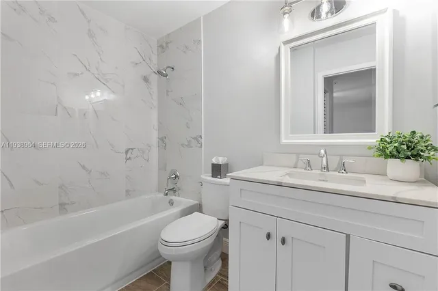 a bathroom with a granite countertop sink a toilet and shower