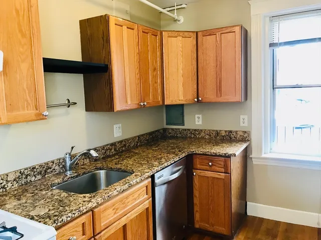 a kitchen with granite countertop a sink a stove and cabinets
