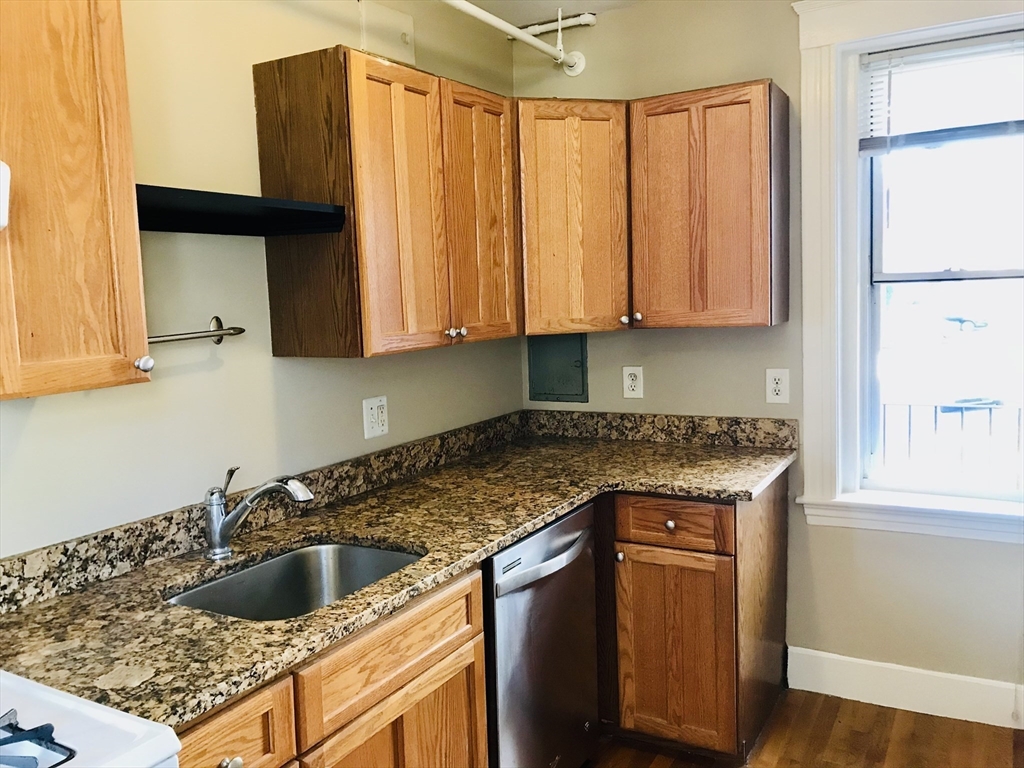 1607 Commonwealth Avenue, Unit 14 Boston, MA 02135 - Photo 4 of 11 a kitchen with granite countertop a sink a stove and cabinets