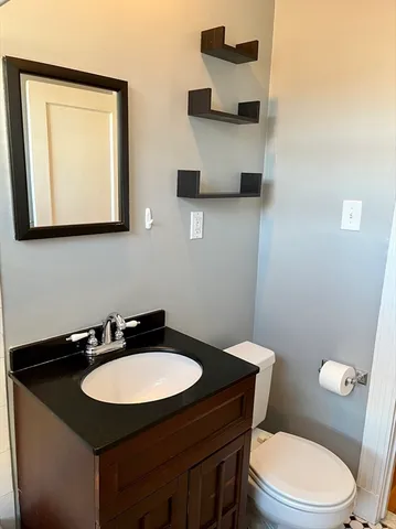 a bathroom with a granite countertop sink a toilet and mirror