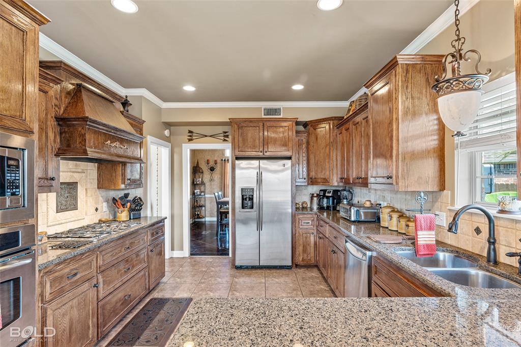 10040 Loveland Court Shreveport, LA 71106 - Photo 11 of 26 a kitchen with stainless steel appliances granite countertop a refrigerator a stove and a sink with wooden cabinets