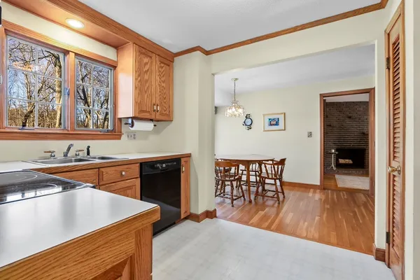 a kitchen with stainless steel appliances granite countertop a stove a sink dishwasher a microwave oven and a dining table with wooden floor