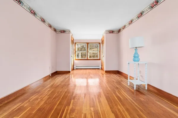 a view of an empty room with wooden floor and a window