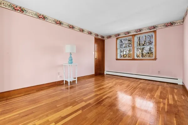a view of an empty room with a window and wooden floor