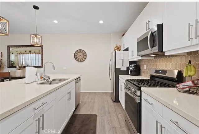 a kitchen with a sink a stove and a clock on the wall