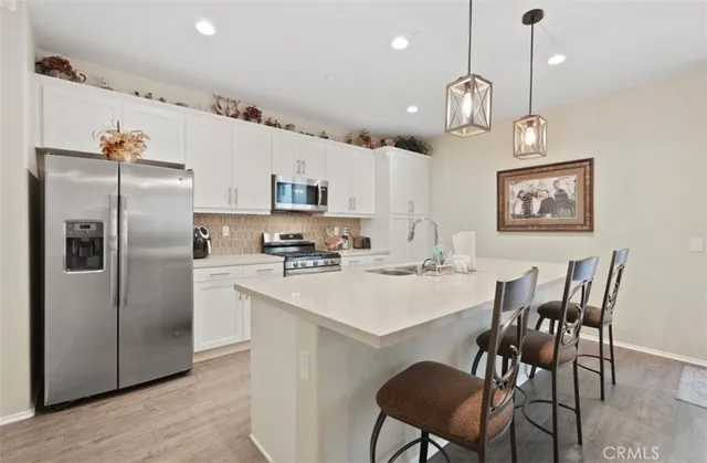 a kitchen with stainless steel appliances a refrigerator a stove a sink a dining table and chairs