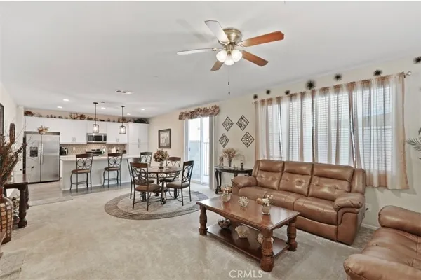 a living room with furniture kitchen view and a chandelier