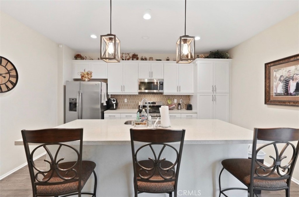2248 Ridge Court Perris, CA 92571 - Photo 4 of 48 a kitchen with stainless steel appliances granite countertop a sink a stove a dining table and chairs with wooden floor