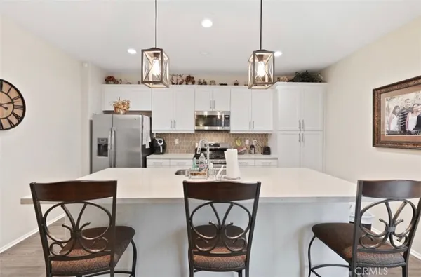 a kitchen with stainless steel appliances granite countertop a sink a stove a dining table and chairs with wooden floor
