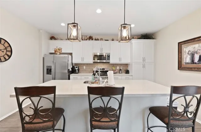 a kitchen with stainless steel appliances granite countertop a sink a stove a dining table and chairs with wooden floor