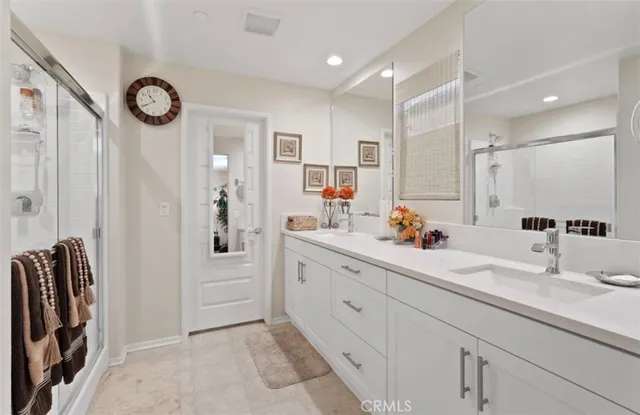 a bathroom with a double vanity sink mirror and shower