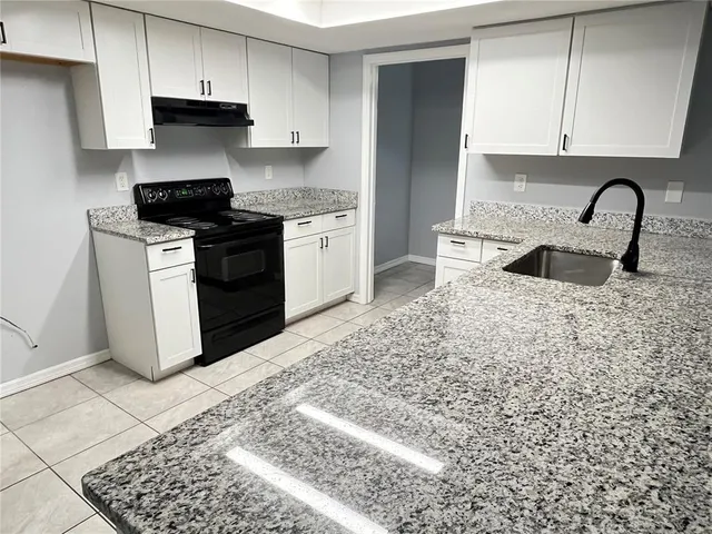 a kitchen with granite countertop a stove a sink and a microwave