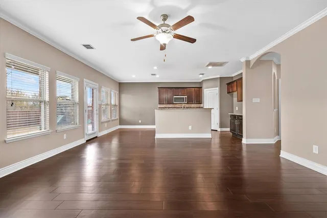 a view of an empty room with a kitchen and wooden floor